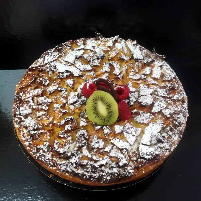 Tarte fine aux pommes saupoudrée de sucre, garnie de kiwi et de fruits rouges